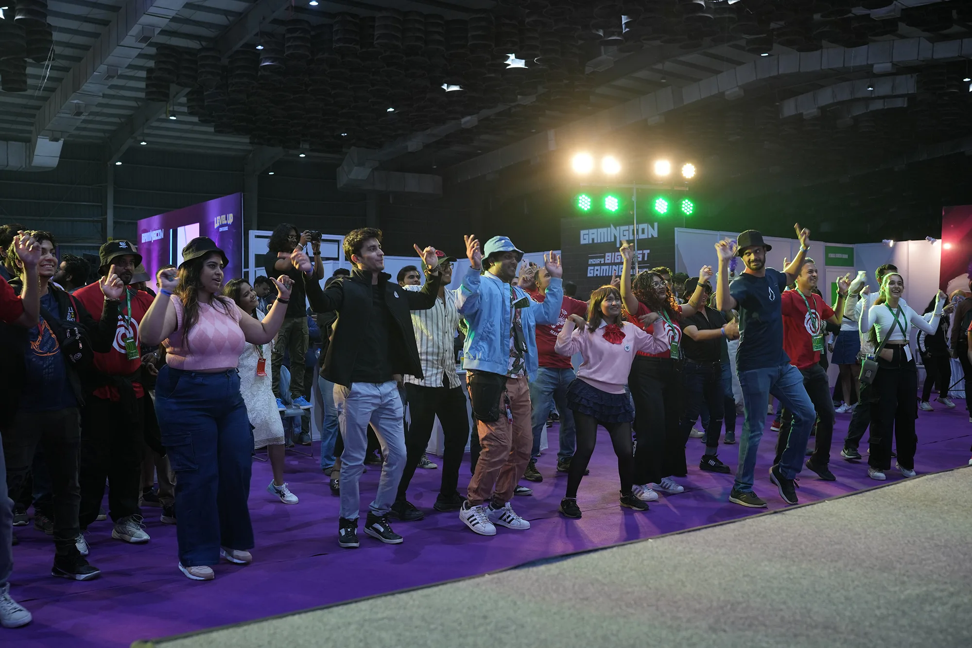 GamingCon festival attendees enjoying interactive dance activity on purple floor with stage lighting