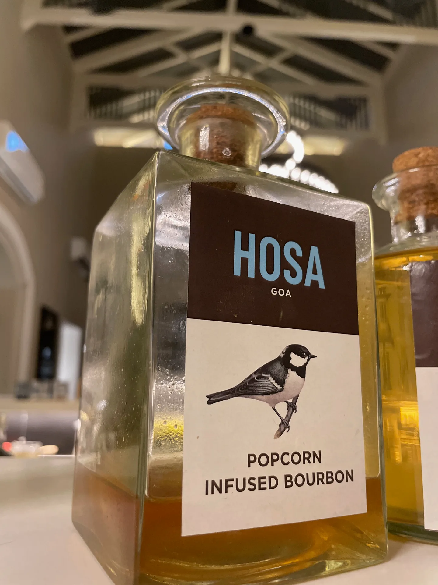 HOSA GOA - Branded popcorn infused bourbon bottle with bird illustration