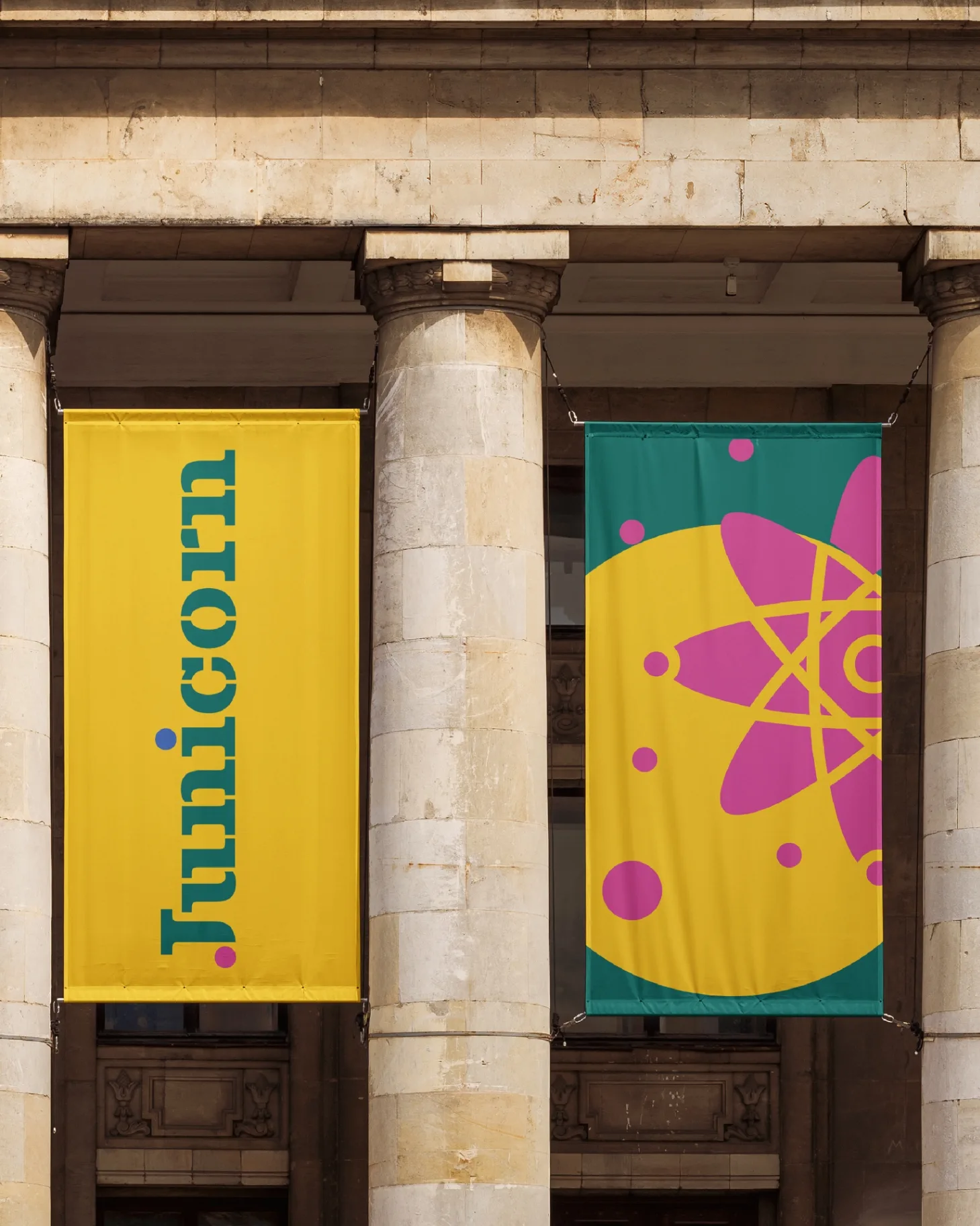 JUNICORN - Hanging banners showing wordmark and graphic elements in yellow and teal