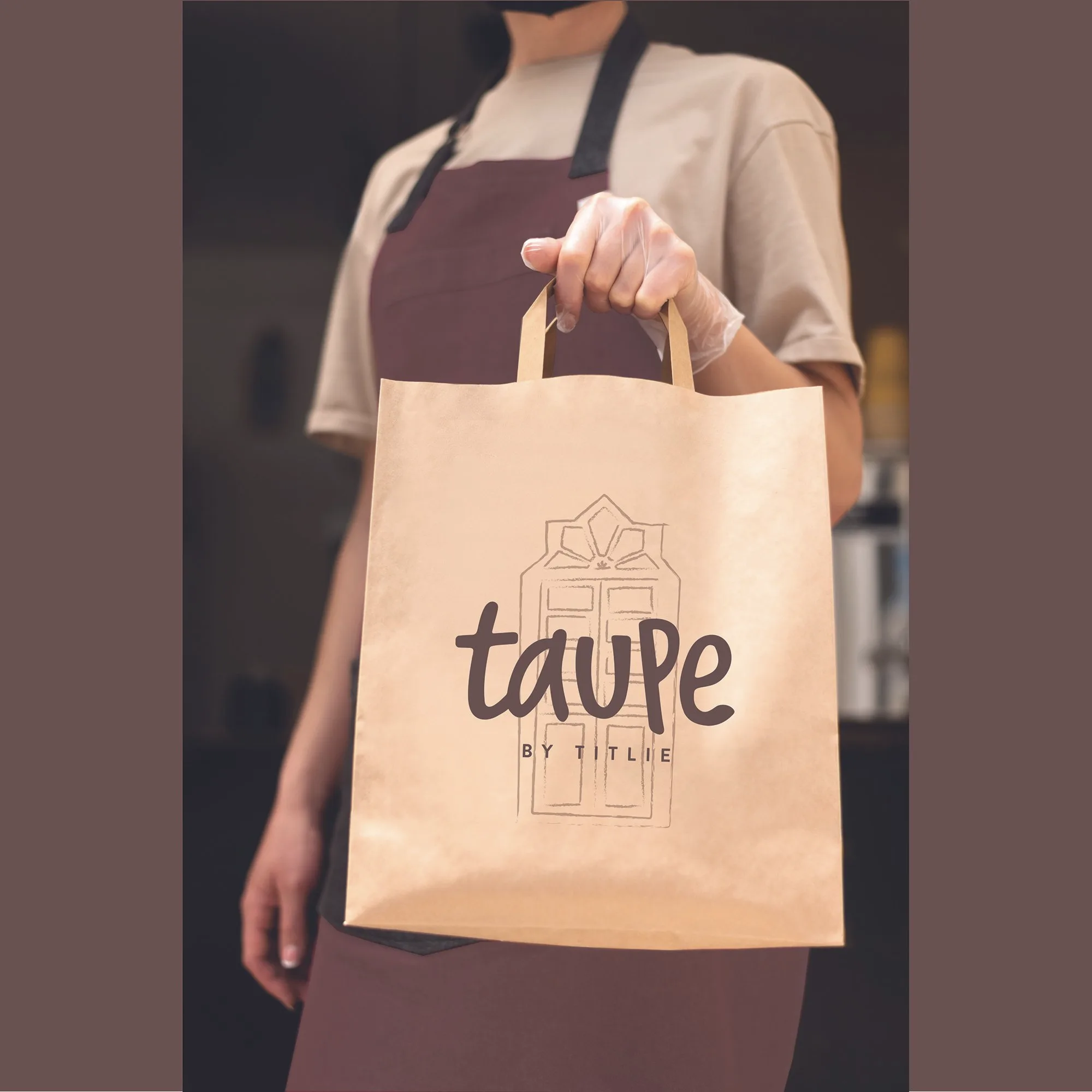 TAUPE branded takeaway bag held by chef showing logo and Portuguese door architectural motif