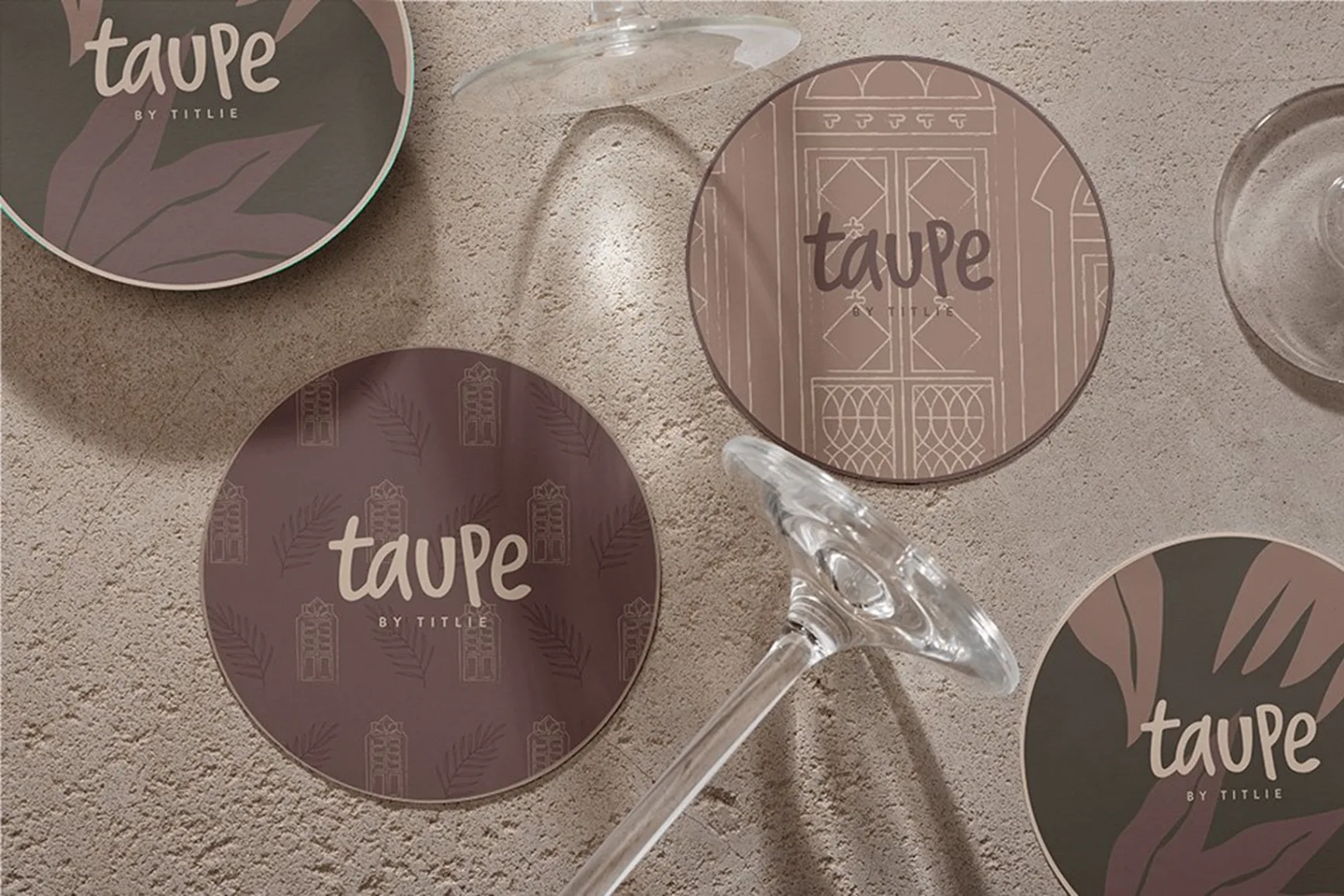 TAUPE branded coasters collection showcasing various design patterns including botanical leaves, Portuguese doors, and brand logo variations
